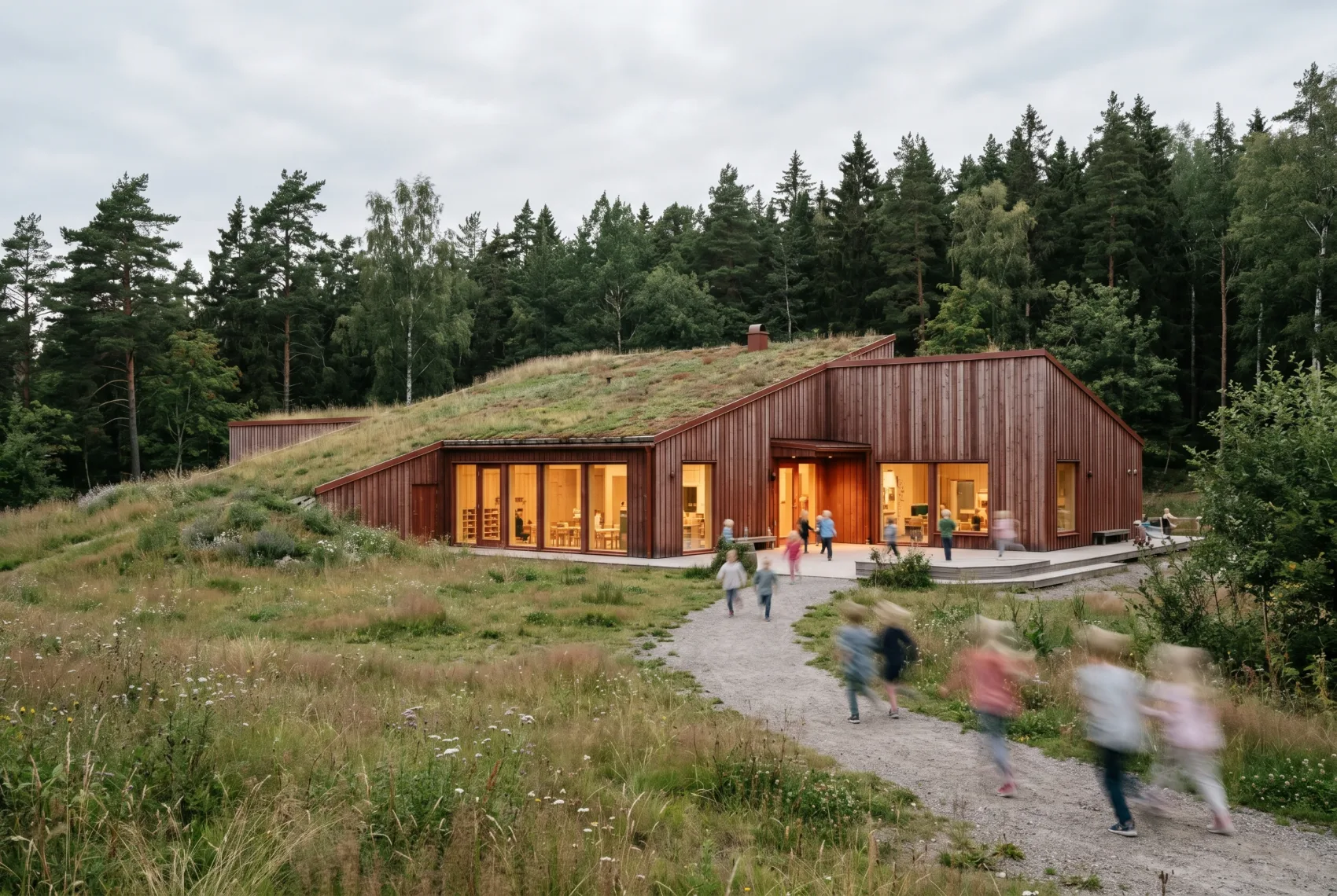 Architectural visualisation — a forest kindergarten with a green living roof set into a meadow slope, children blurred along the path