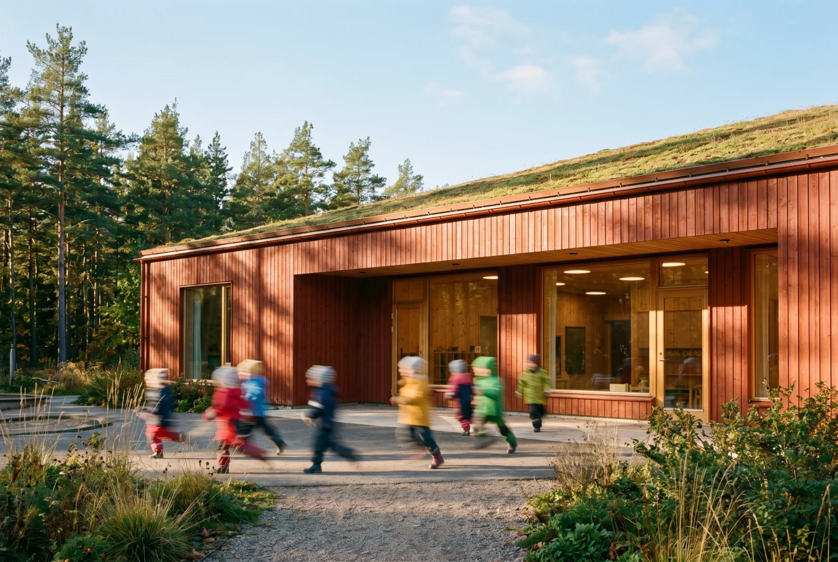 Architectural visualisation — children in colourful coats running past the sunlit red timber facade, long-exposure blur