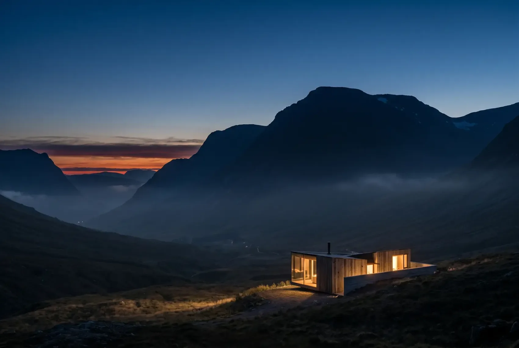 Architectural visualisation — the retreat small beneath a great mountain as the last light fades over the ridge
